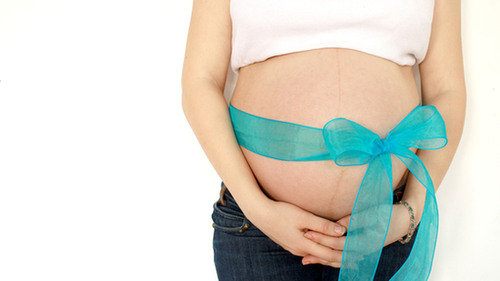 Ciążowy brzuch przewiązany wstążką